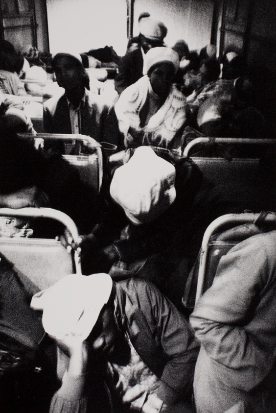 3:30 a.m. Going to work: The interior of this bus is dimly lit by a small green bulb at one end of the aisle and a small red one at the other. But once it reaches the highway, the headlights of the stream of buses and taxis taking workers to Pretoria are an almost continuous glare through the rear window, from the series "The Transported of KwaNdebele"